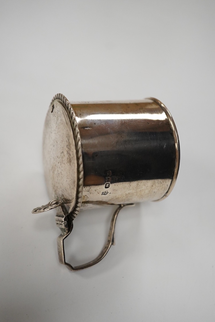An Edwardian silver mug, on claw and hoof feet, William Hutton & Sons, London 1909, height 83mm, together with a silver butter shell, mustard pot and a silver five bar toastrack, 17oz.